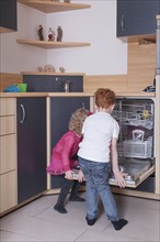 Girl (4-5) and boy (8-9) loading dishwasher