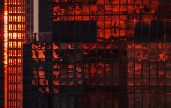 USA, New York State, New York City, Reflection on glass facade of office building at sunset.