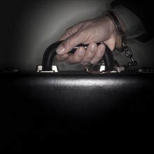 Hand connected to briefcase with handcuffs.