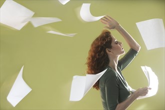 Mature woman scattering papers around herself.
