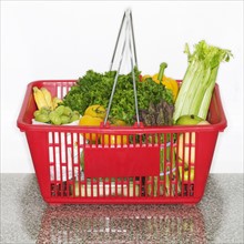 Fruits and vegetables in grocery basket on countertop.