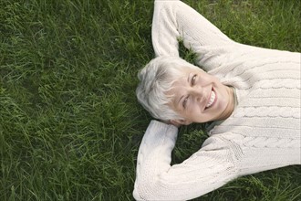 Smiling mature woman lying on grass.