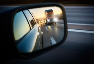 Truck on road reflecting in rear view mirror.
