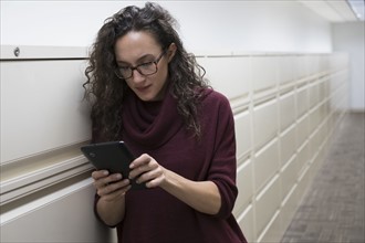 Young woman using digital tablet in corridor.