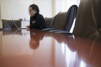 Young business woman sitting in conference room with laptop.