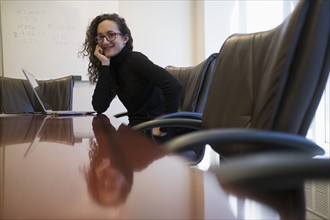 Portrait of young business woman sitting in conference room with laptop.