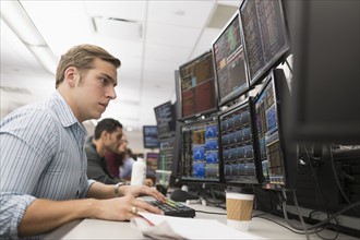 Young traders analyzing computer data.