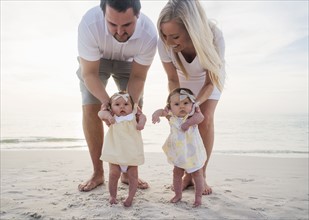Happy family with two baby girls (2-5 months) at beach