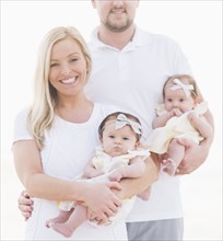 Studio shot portrait of happy family with two baby girls (2-5 months) on white background