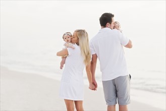 Parents walking with babies (2-5 months) along seashore