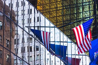 USA, New York, New York City, American flag reflection in glass facade of office building