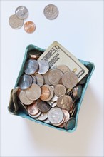 Coins and banknotes in carton box on white surface