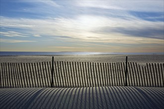 USA, New York, Lond Island, Fence by beach at sunset