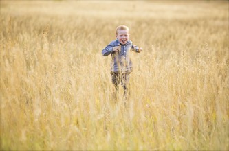 Boy (4-5) running in dry grass