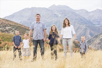 USA, Utah, Provo, Family with three children (4-5, 6-7, 8-9) standing in field
