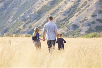 Father with two daughters (4-5, 8-9) walking in field