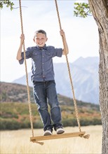 Boy (6-7) standing on swing