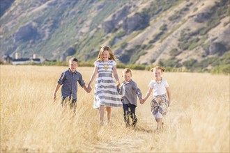 USA, Utah, Provo, Boys and girls (4-5, 6-7, 8-9) walking in field, holding hands