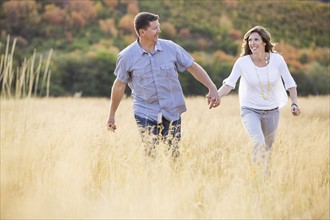 Smiling couple holding hands while walking in field