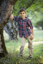 Smiling boy standing by cherry tree