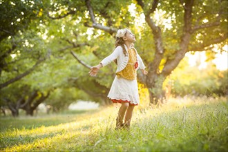 Carefree girl spinning in orchard with outstretched arms