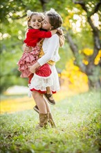 Girl holding and kissing sister in cherry orchard