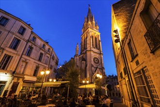 France, Occitanie, Montpellier, Sidewalk cafe and St. Anne Church at dusk