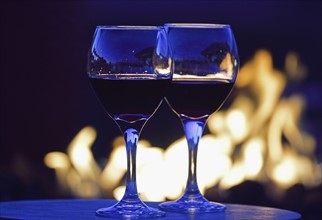 Glasses of red wine against fire pit at night