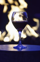 Glass of red wine against fire pit at night