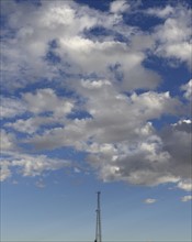 Communication tower against cloudy sky