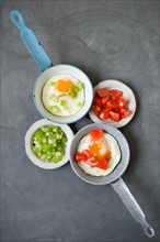 Fried eggs and vegetables on frying pans and plates