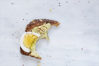 Missing bite of toasted bread with avocado and hard boiled egg