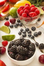Raspberries in bowl surrounded by other fruits