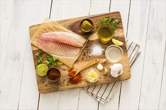 Raw tilapia and ingredients on cutting board