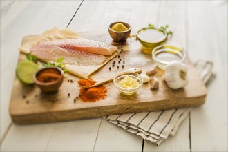 Raw tilapia and ingredients on cutting board