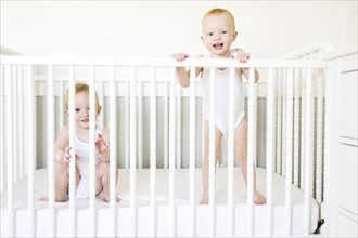 Twin brothers (12-17 months) playing in crib