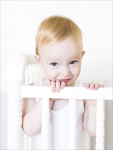 Portrait of baby boy (12-17 months) standing in crib