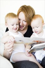 Mother and sons (12-17 months) reading picture book