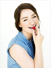 Woman wearing blue top eating raspberry