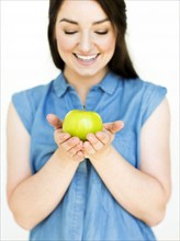 Woman wearing blue top holding green apple