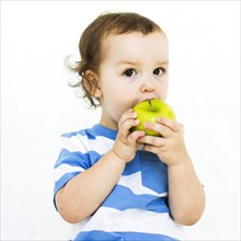 Boy (4-5) wearing t-shirt eating green apple