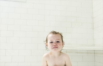 Sad boy (4-5) with wet hair in bathroom
