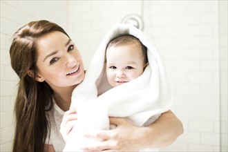 Mother wrapping son (4-5)  in towel in bathroom