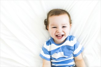 Boy (4-5) lying on bed and laughing