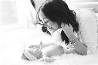 Mother playing with daughter (0-1 months) on bed