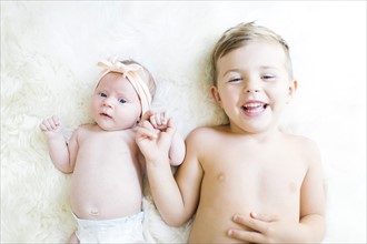 Brother (4-5) and sister (0-1 months) lying on bed