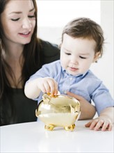 Mother teaching son (4-5) how to save money