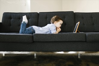 Young boy (4-5) lying on sofa