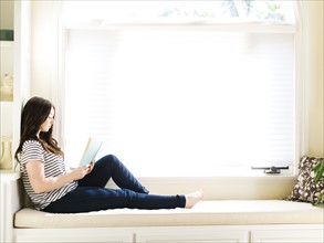 Woman sitting on couch with book in hands