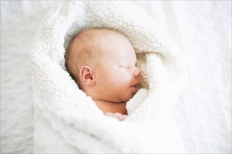 Baby boy (2-5 months) sleeping in white blanket